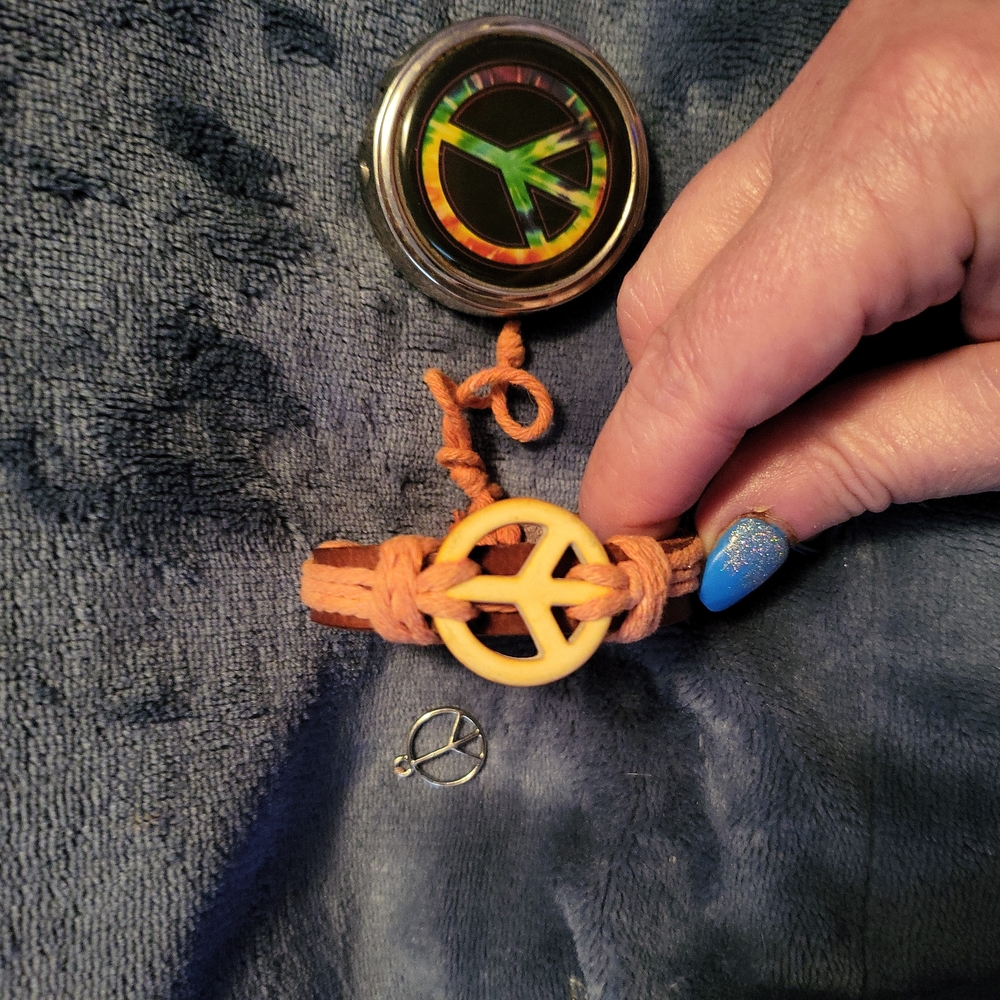 Peace-related grouping of three items. A pendant, a bracelet and a pill holder.